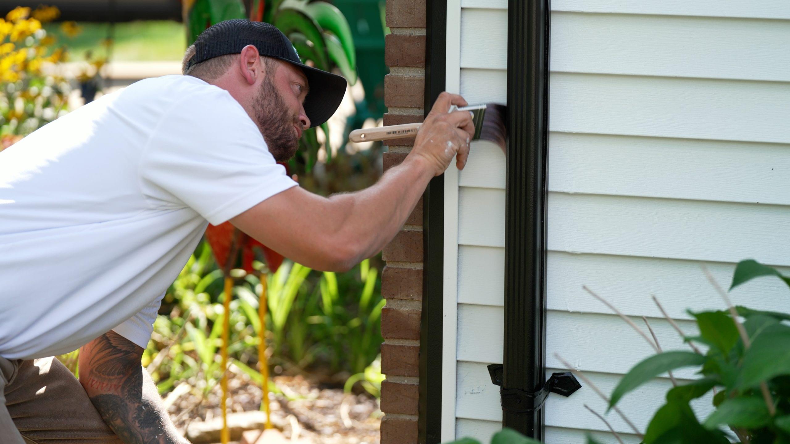 Cutting Edge Painting LLC owner, Logan, painting a home's exterior for info about the company