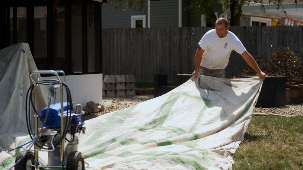 Cutting Edge Painting Employee spreading drop cloth outside home. Painters Near Me South Bend for How to Choose the Best Painting Contractor in South Bend, Elkhart, and Niles article